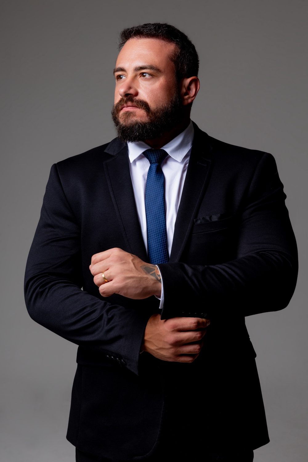 Pablo Dietrich, de terno escuro e gravata azul, ajustando o punho da camisa